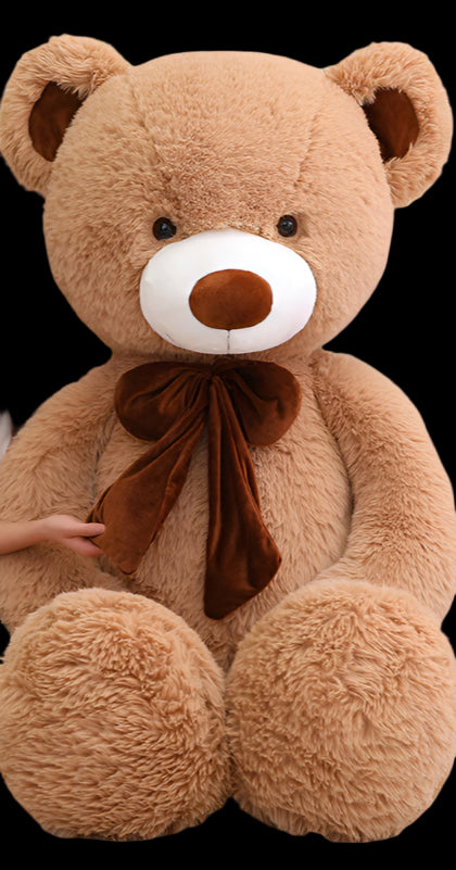 Person sitting on a couch with a large teddy bear in a room with a 'smile zone' sign.
