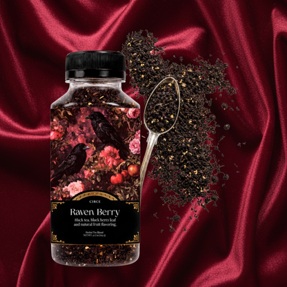 A bottle of Cuck Rack Raven Berry herbal tea with a black cap, shown next to a metal spoon filled with loose dried black berries and tea leaves on a white background.