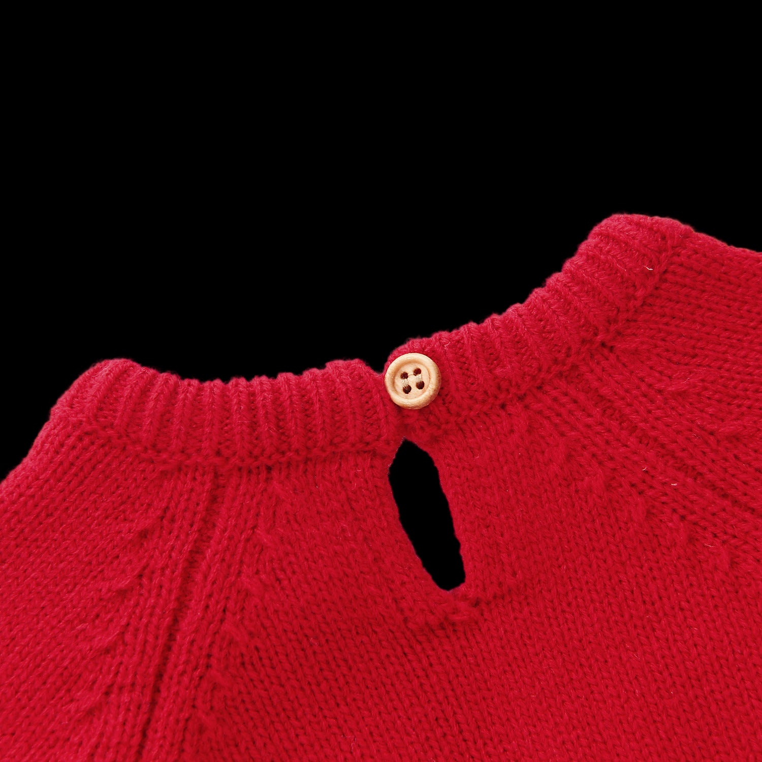 Close-up of a red knitted garment with a button on a white background