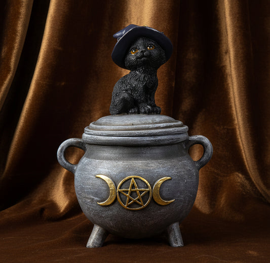 A decorative cauldron figurine with a black cat wearing a witch hat sitting on top, set against a plain white background.