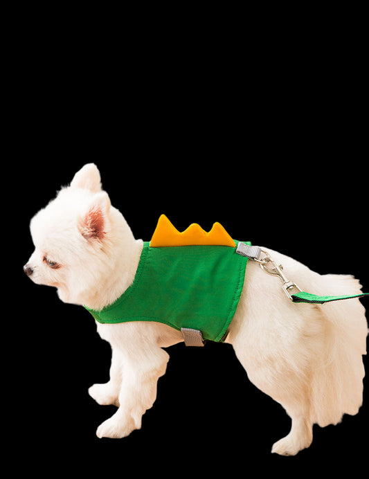 Small white dog wearing a green dinosaur costume on a wooden floor