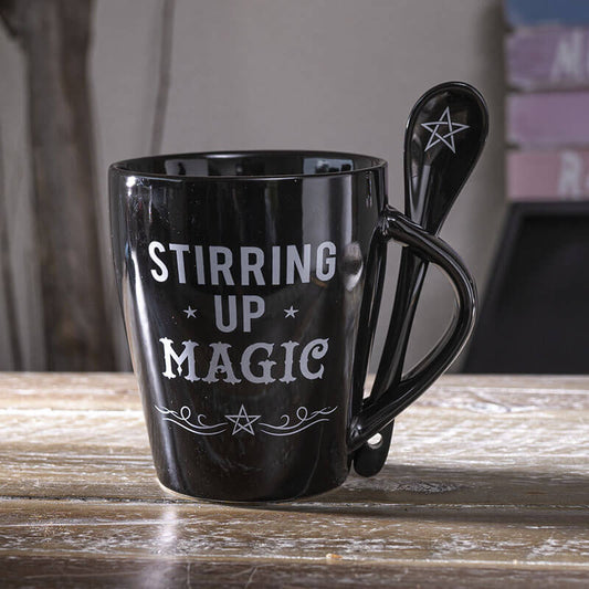 Black mug with 'Stirring Up Magic' text and a spoon on a wooden surface