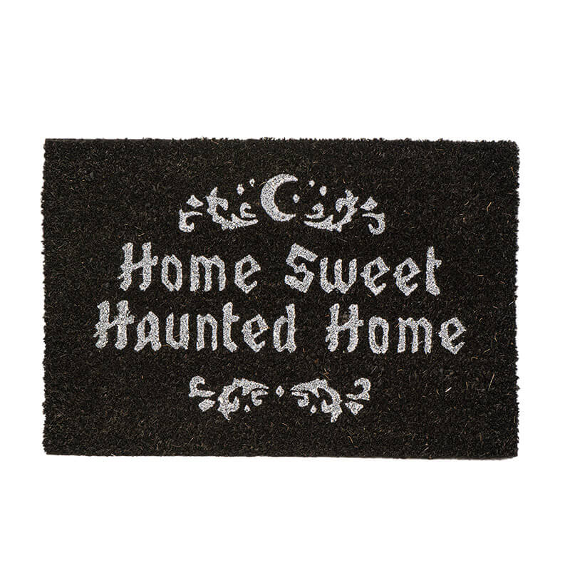 A rectangular black coir doormat with white gothic-style text reading 'Home Sweet Haunted Home' and decorative white motifs at the top and bottom, shown on a plain white background.