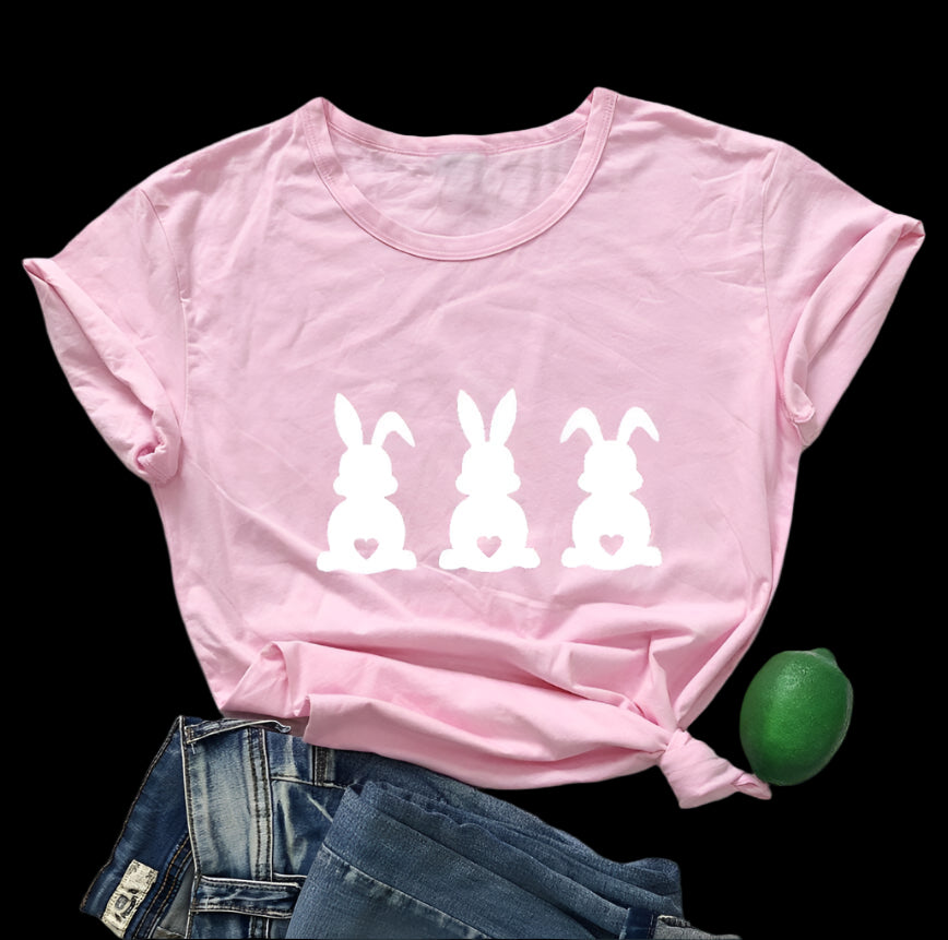 Pink t-shirt with white bunny designs on a wooden surface