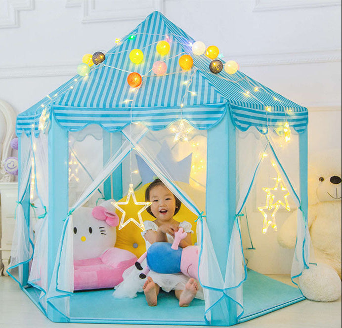 Child playing inside a blue striped play tent with string lights and plush toys.