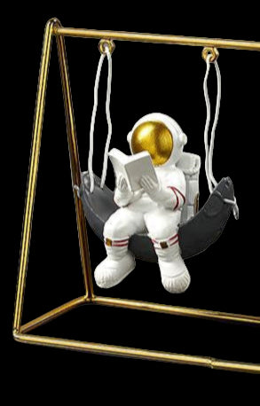 Small astronaut figurine on a swing with a calendar in a gold frame on a dark surface.