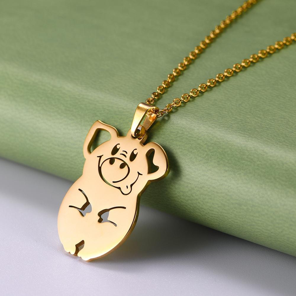 Gold pig shaped pendant on a chain against a green and gray background