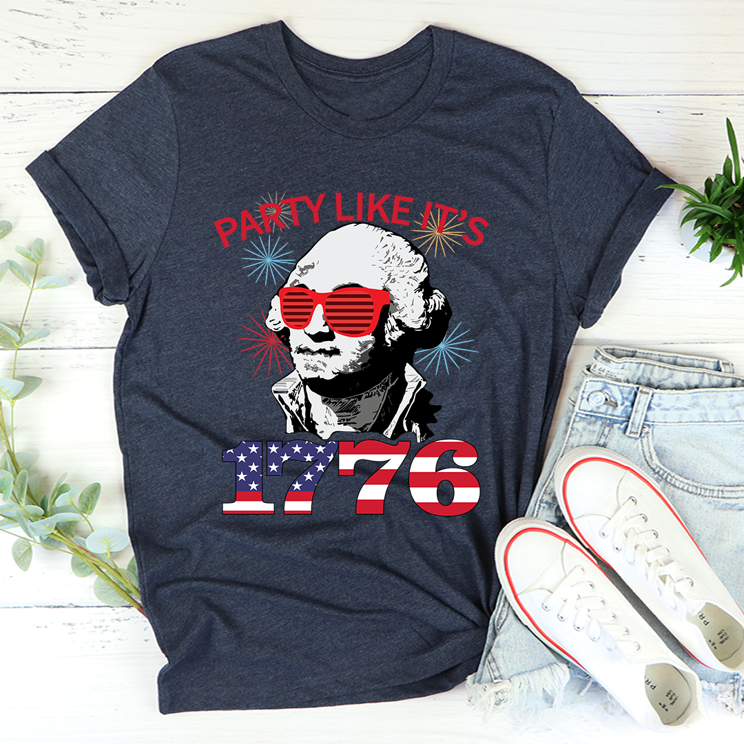 Navy blue t-shirt with a graphic of George Washington wearing sunglasses and text 'Party Like It's 1776' on a wooden surface.