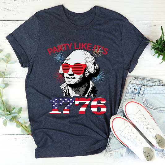 Navy blue t-shirt with a graphic of George Washington wearing sunglasses and text 'Party Like It's 1776' on a wooden surface.