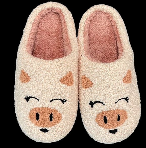 Pair of cream-colored slippers with pig face design on a white background