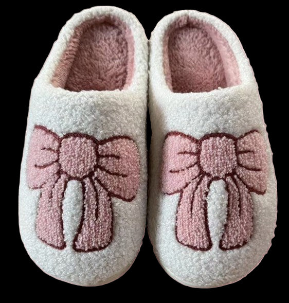 Pair of white slippers with pink bows on a pink background