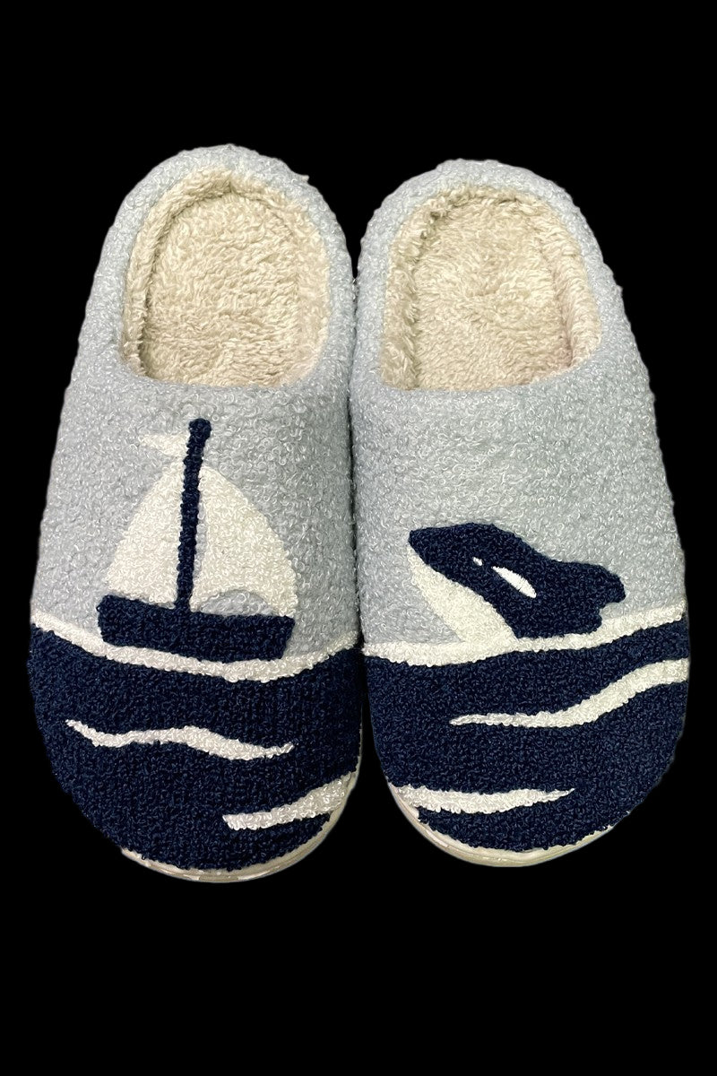 Pair of slippers with sailboat and whale design on a light blue background