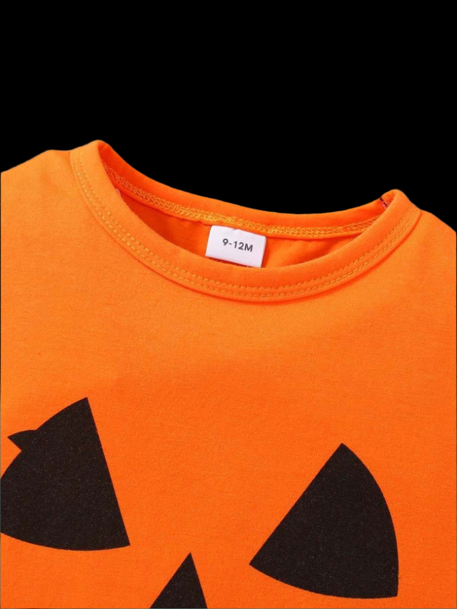 Orange shirt with black cat face design on a wooden surface