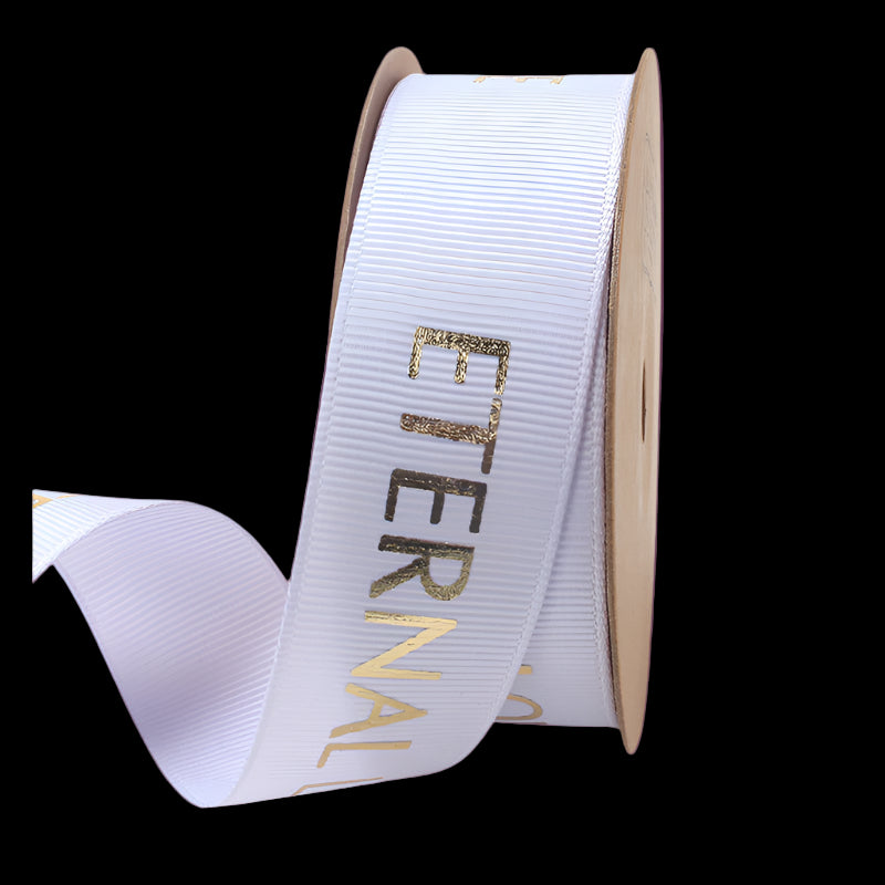 Spool of white ribbon with 'Eternal' text in gold on a white background