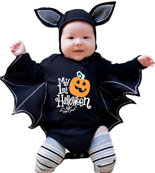 Baby wearing a Halloween-themed outfit with bat wings and a pumpkin design on a textured surface.