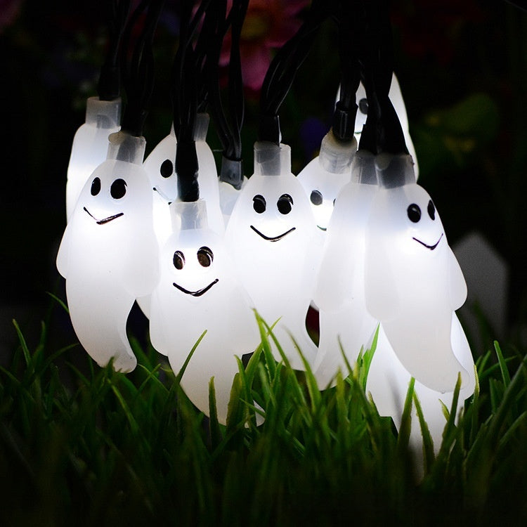 String of ghost-shaped lights on grass at night