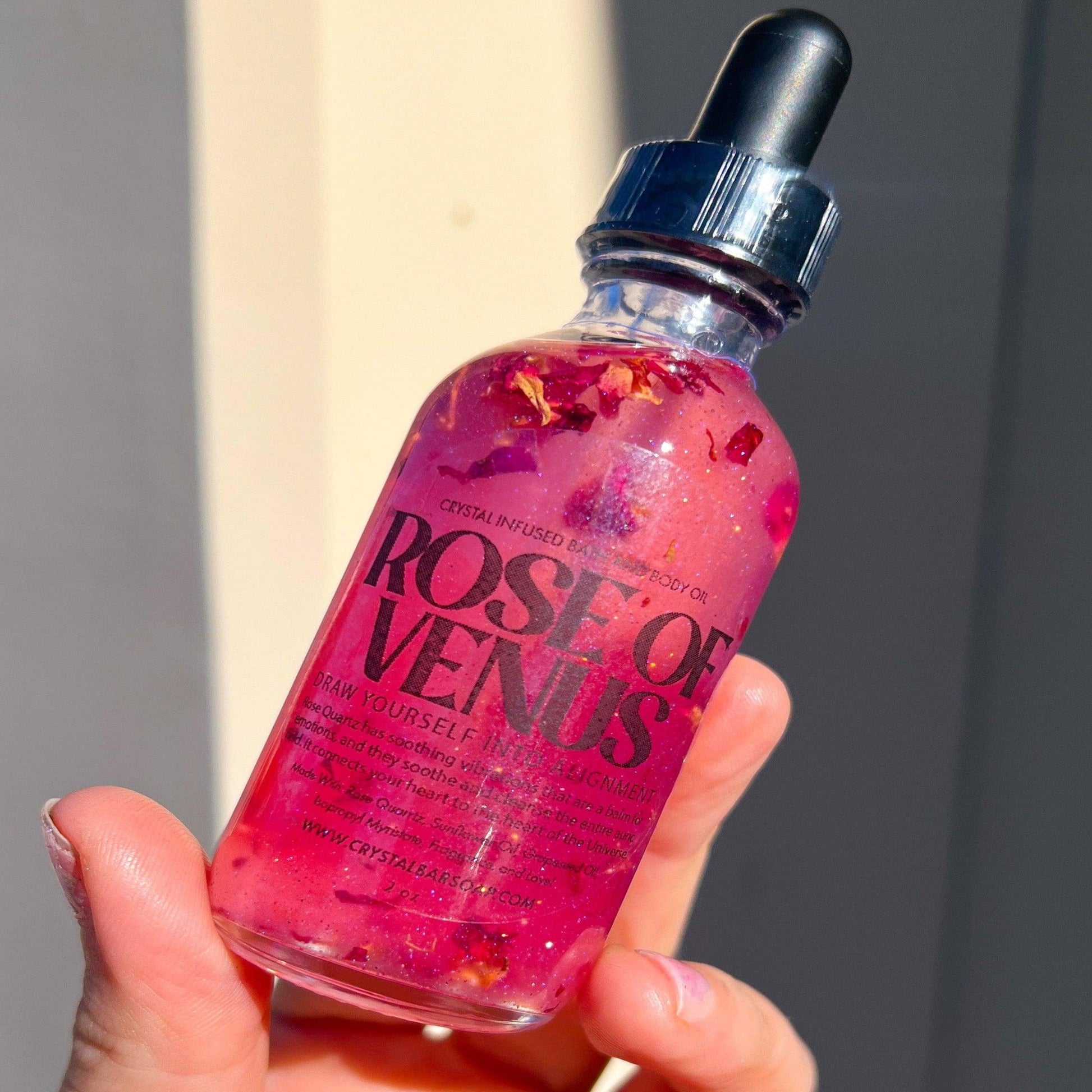 Bottle of 'Rose of Venus' with a dropper held in a hand against a neutral background