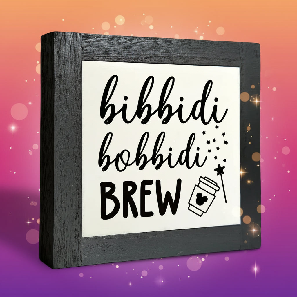 Decorative sign with 'bibbidi bobbidi BREW' text and a coffee cup icon in a black frame.