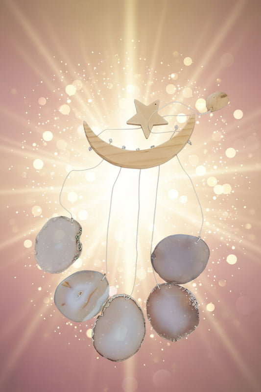 Decorative hanging with moon, star, and shells on a dark surface