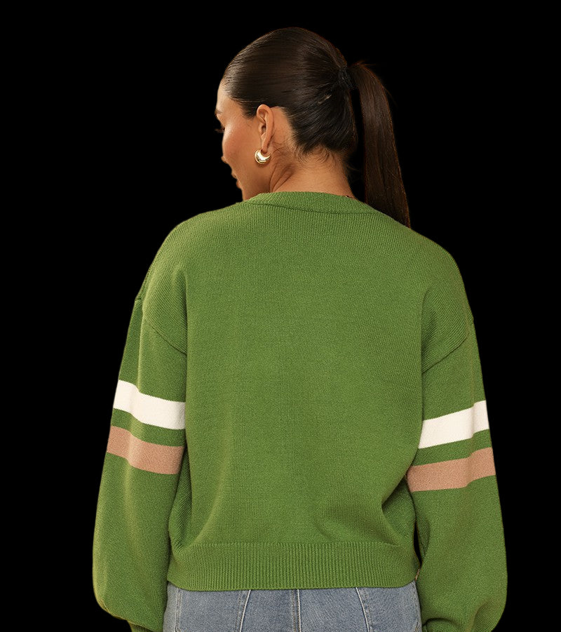 Person wearing a green sweater with white and brown stripes on sleeves against a beige background