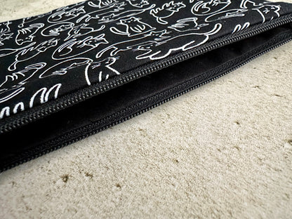 Black pouch with white cat pattern on a beige surface