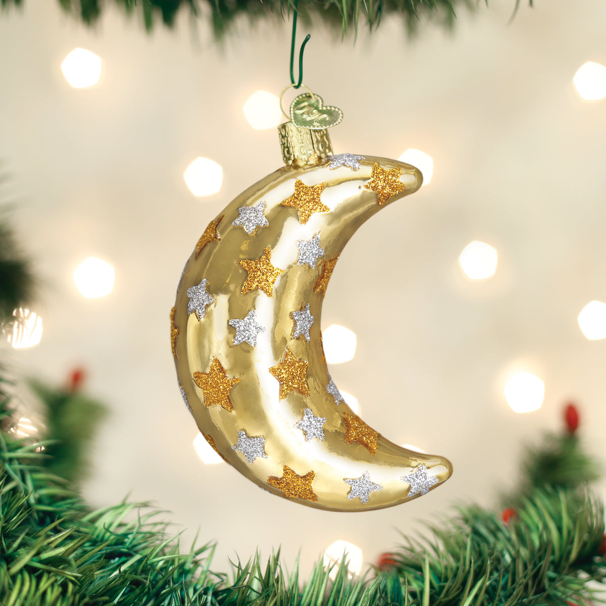 Decorative gold moon ornament with stars on a Christmas tree.