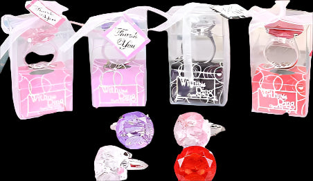 Decorative keychains in small boxes on a table with flowers in the background