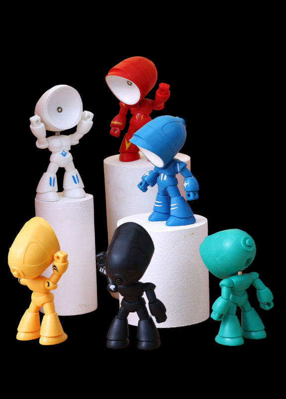 Colorful toy figures on cylindrical white stands against a yellow wall with a pink toy box.