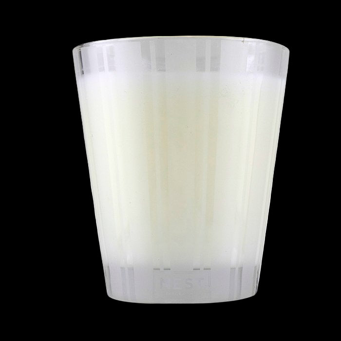 White candle in a glass container on a white background