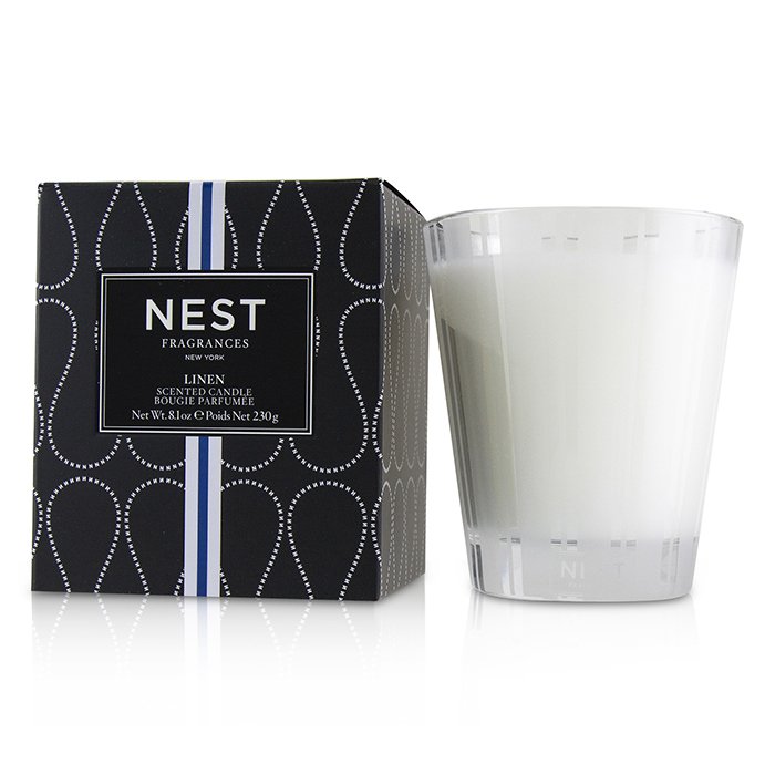 White candle next to its packaging with 'NEST Fragrances' branding on a white background