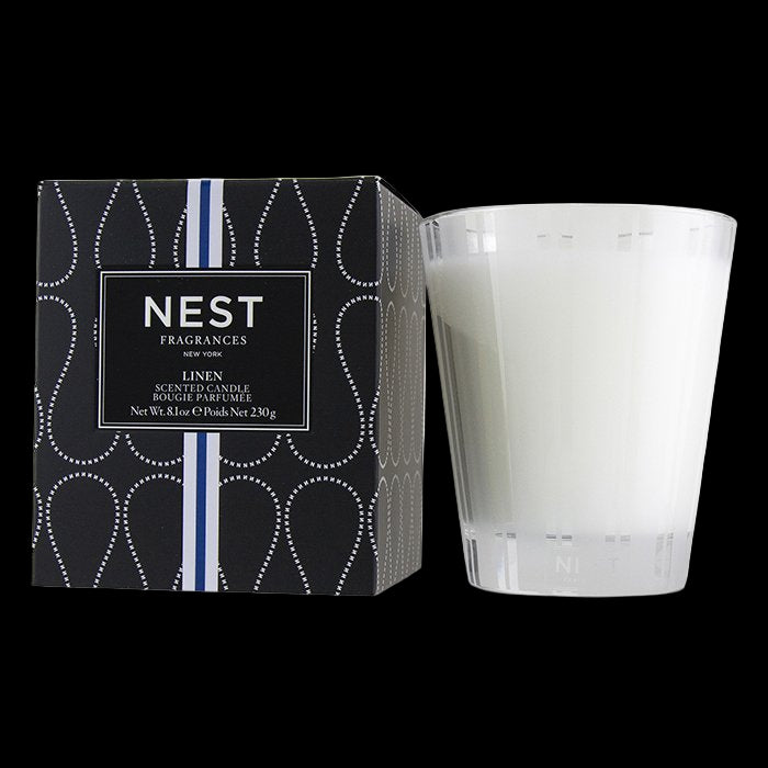 White candle next to its packaging with 'NEST Fragrances' branding on a white background