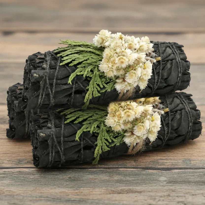 Two black rolled towels with white flowers and green leaves on a wooden surface