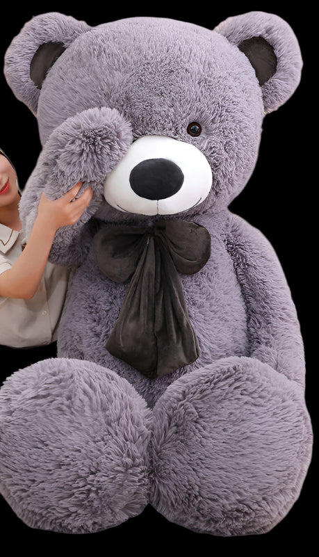 Person holding a large purple teddy bear in a room with a 'smile zone' poster.