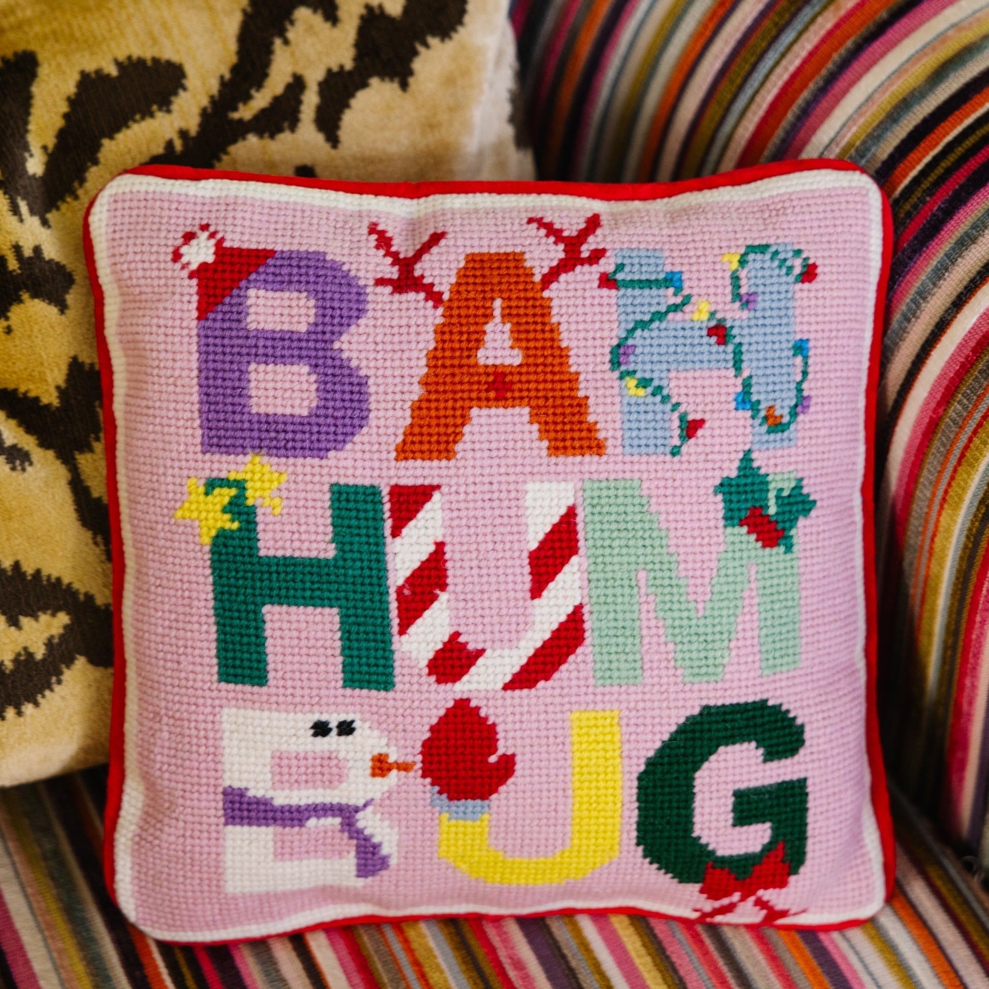 Cross-stitched pillow with colorful letters on a striped couch