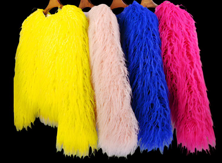 Four colorful fur coats on hangers against a gray background