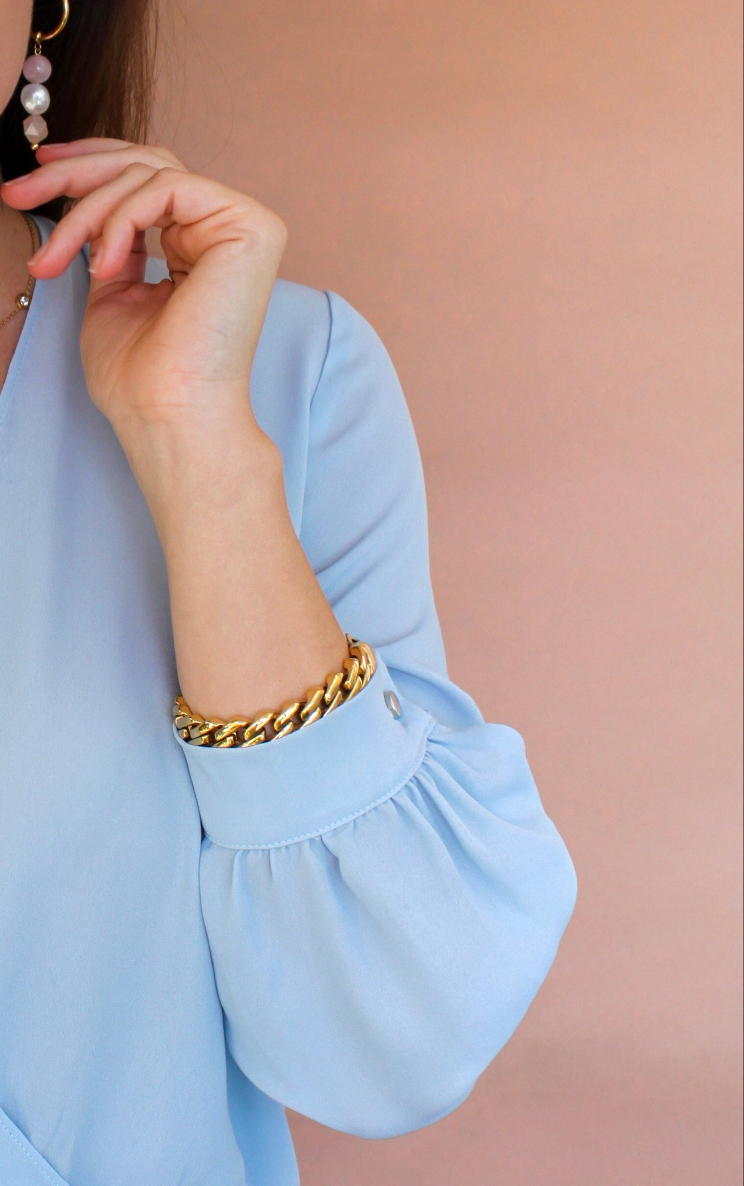 Woman wearing a light blue blouse and jeans against a beige background