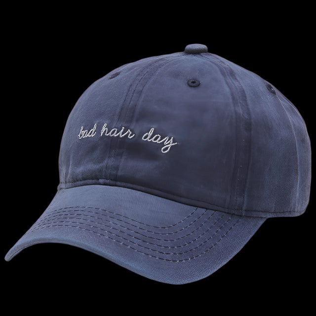 Navy blue cap with 'bad hair day' embroidery on a transparent background
