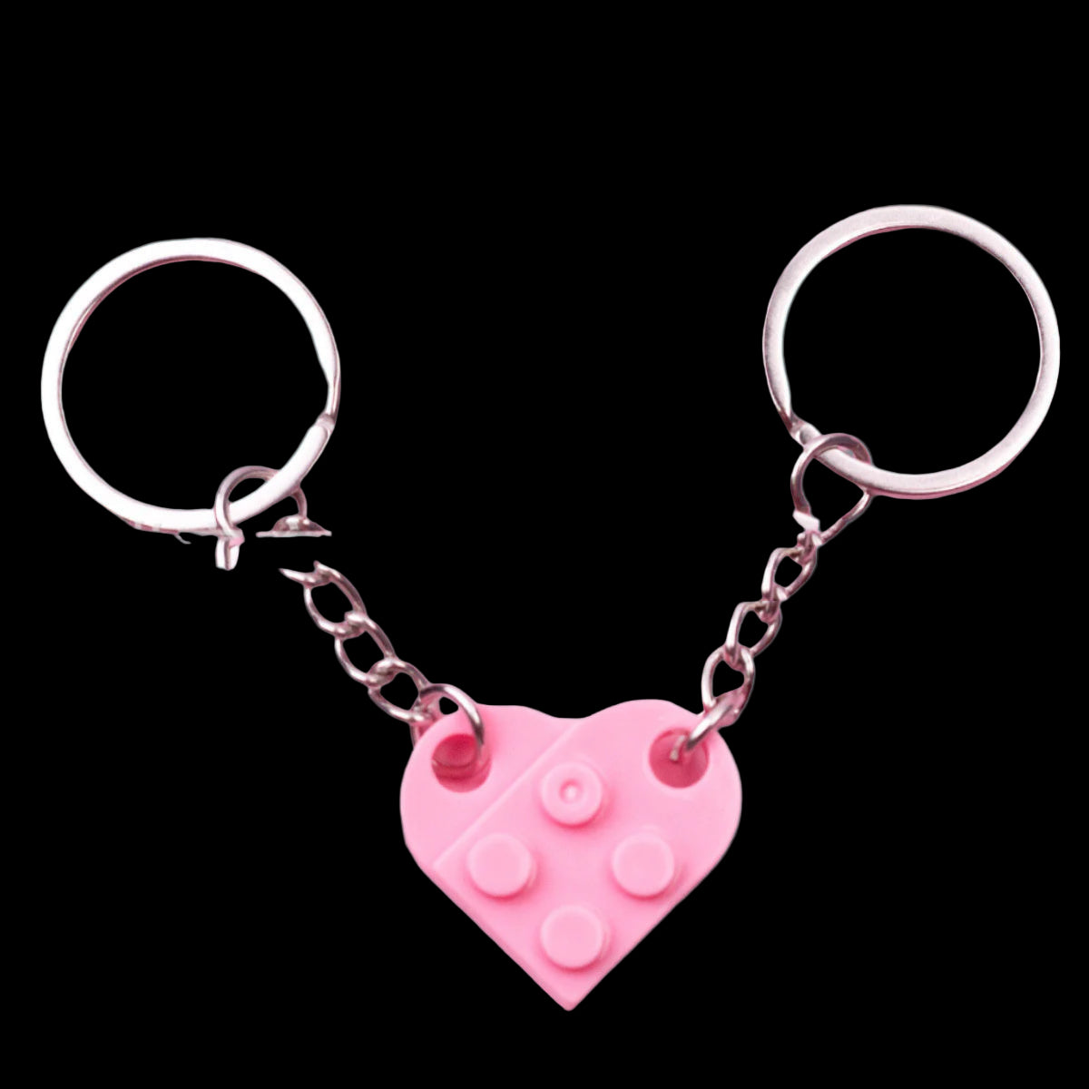 Pink heart-shaped keychain with metal chain on a green background