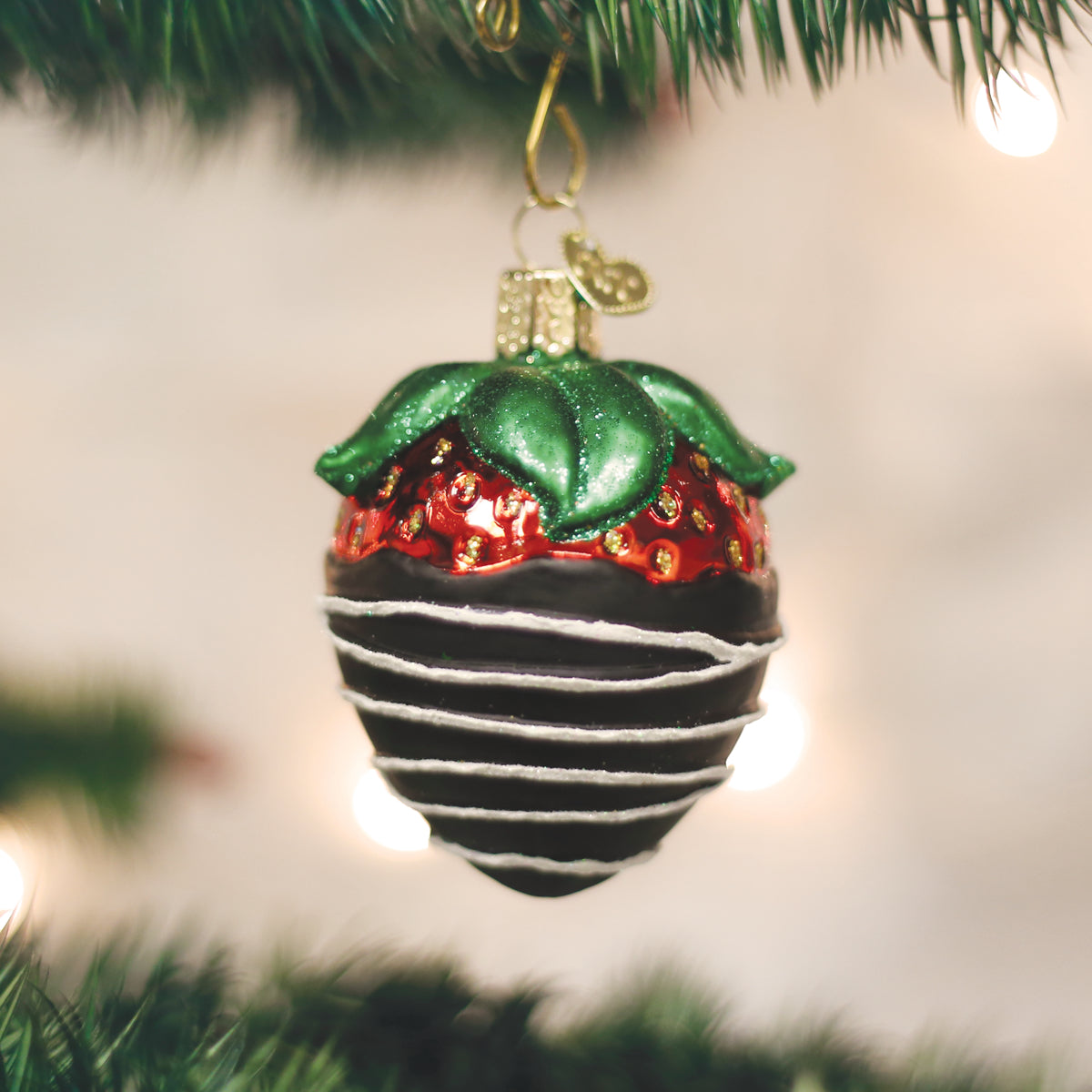 Decorative Christmas ornament on a tree with lights in the background