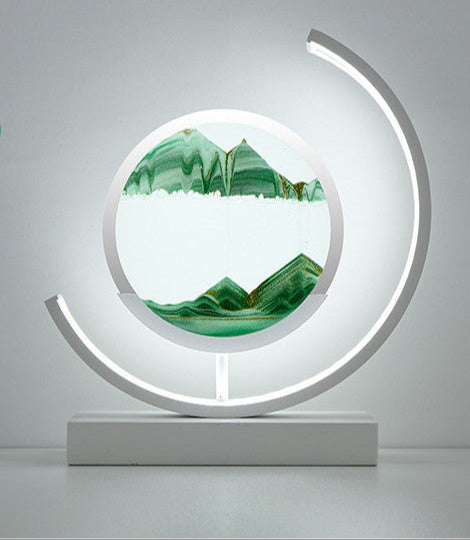 Decorative piece with green mountain design inside a circular frame on a white base against a gray background