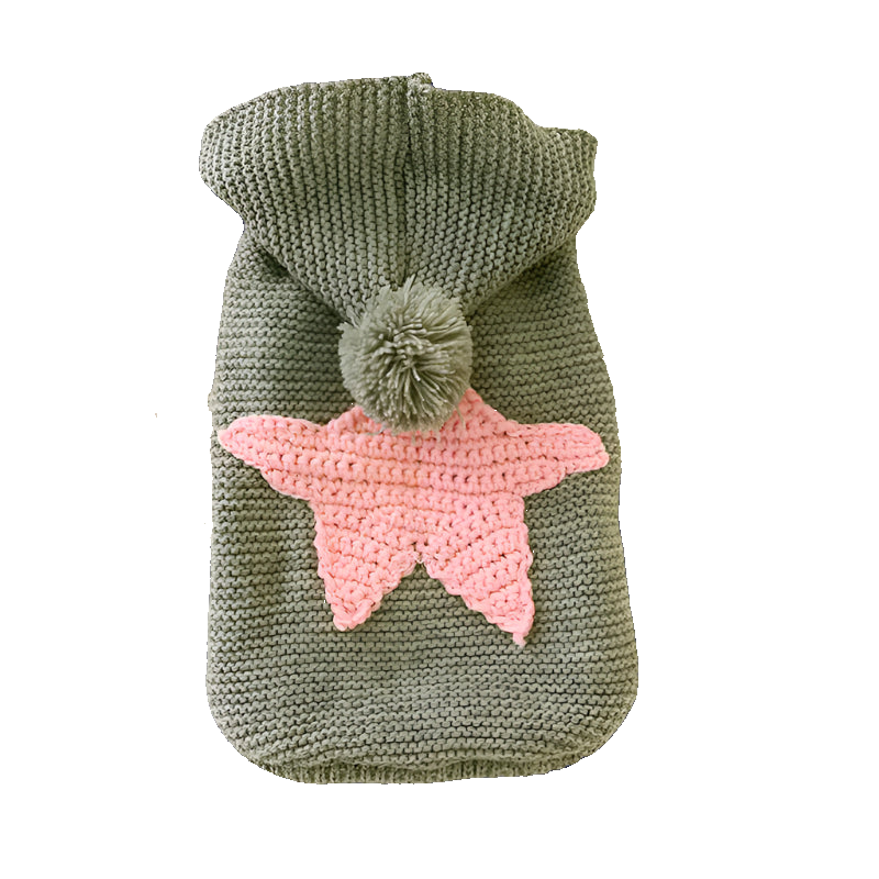 Knitted pouch with a pink star and green pom-pom on a white surface with a magazine in the background.