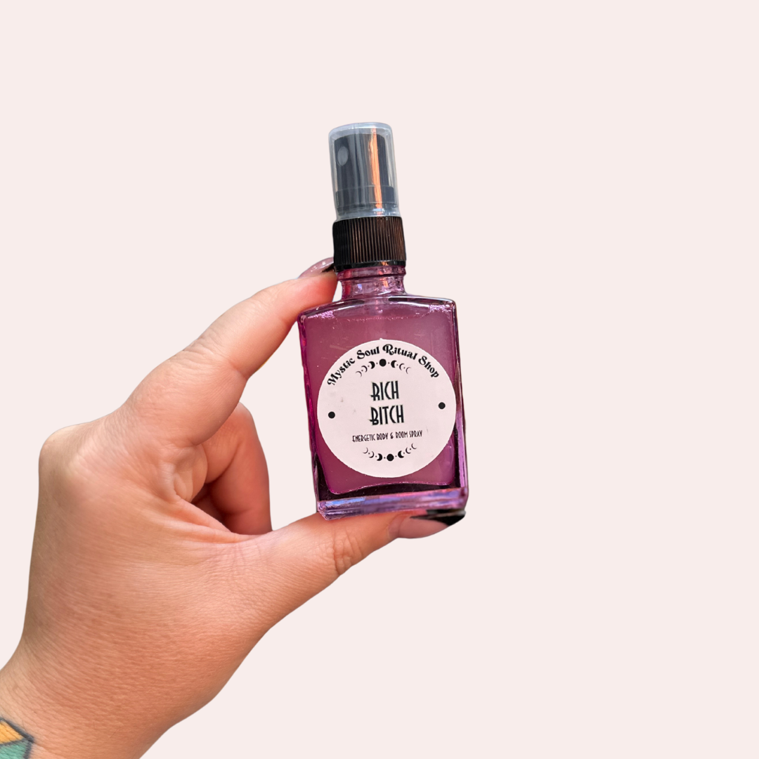 Hand holding a small purple bottle with a label on a light pink background