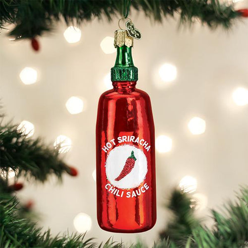 Red Hot Sriracha chili sauce bottle ornament on a Christmas tree with lights in the background