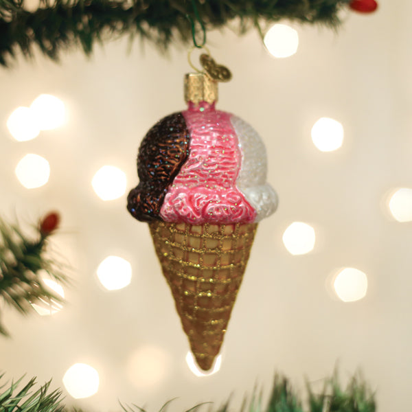 Decorative ice cream cone ornament on a Christmas tree with lights in the background