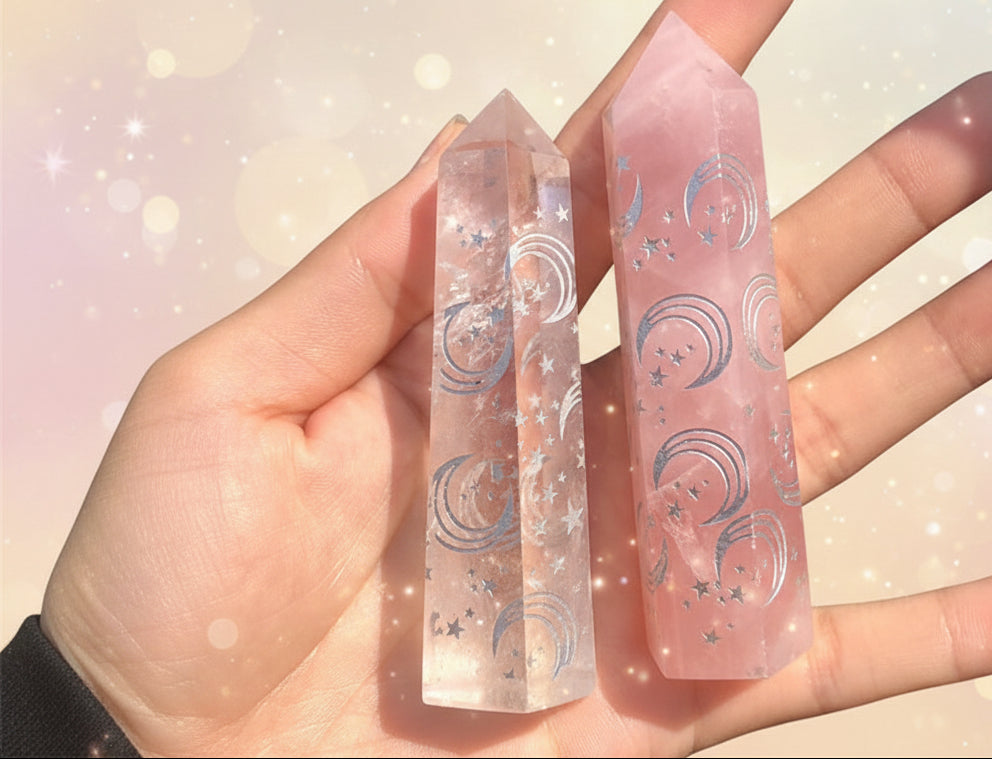 Three pink crystal sticks with engraved designs held in a hand against a blurred background