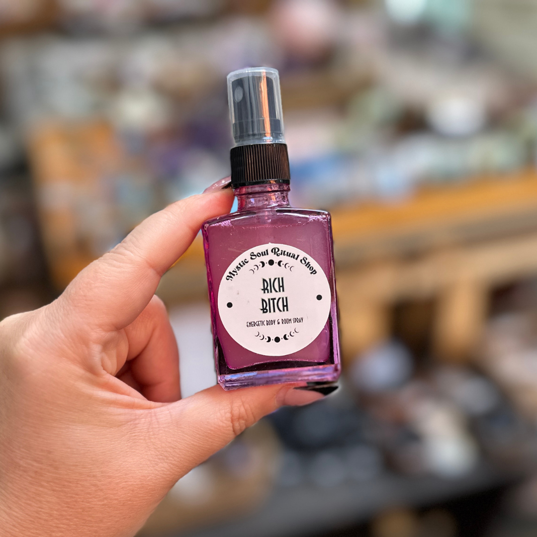 Hand holding a small spray bottle with a label on a blurred background