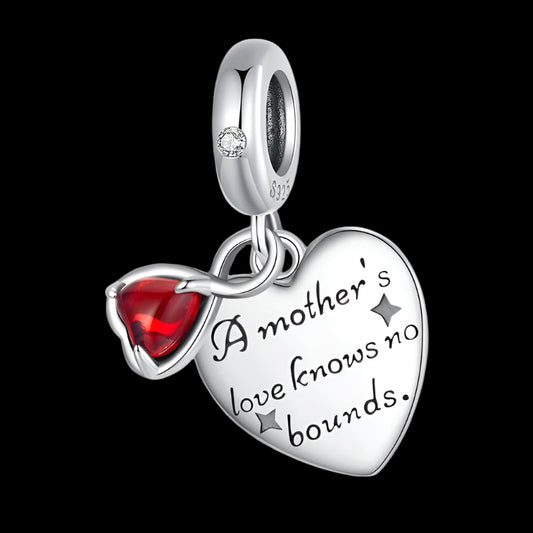 Silver heart-shaped charm with red gemstone and engraved text on a white background