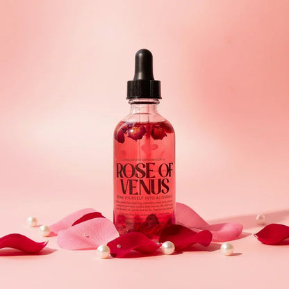 Bottle of 'Rose of Venus' product with rose petals and pearls on a pink background