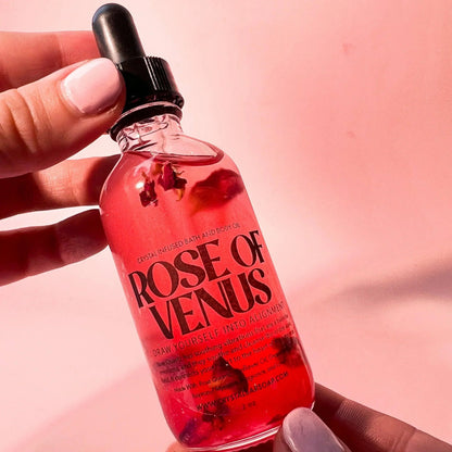 Bottle of 'Rose of Venus' with a dropper held by a hand against a pink background