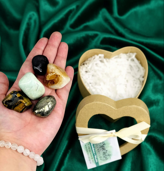 Hand holding colorful stones with a heart-shaped container of white powder on a light background